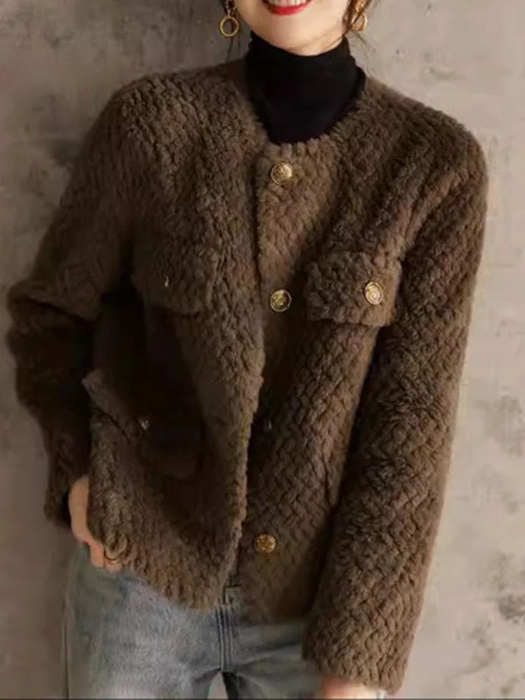 Woman wearing a textured short jacket with gold buttons in a tailored silhouette, viewed from behind._21