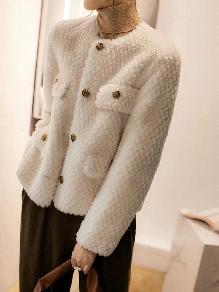 Woman wearing a textured short jacket with gold buttons in a tailored silhouette, viewed from behind._24