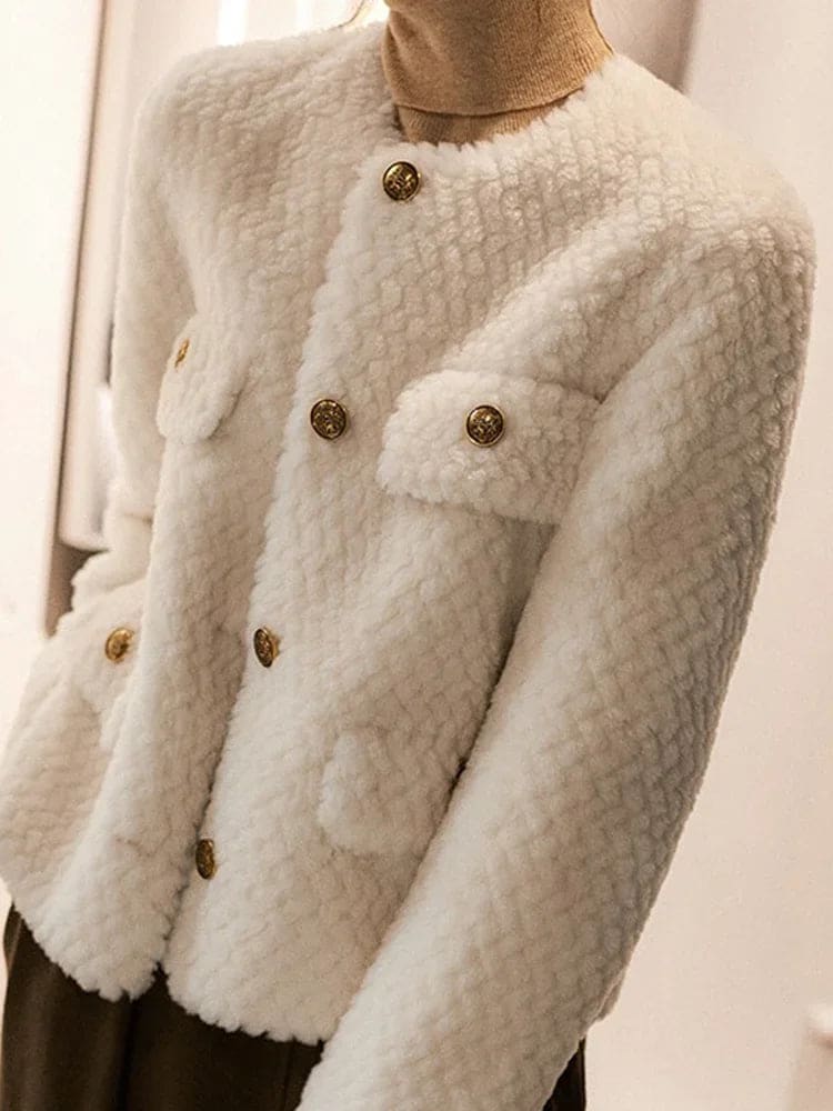 Woman wearing a textured short jacket with gold buttons in a tailored silhouette, viewed from behind._25