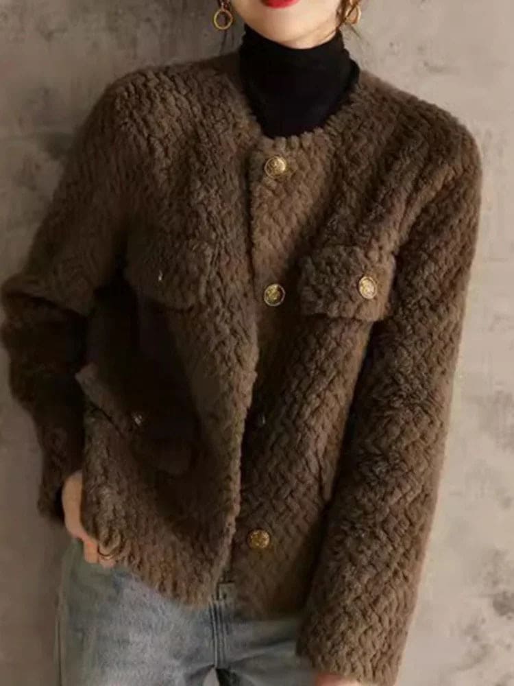Woman wearing a textured short jacket with gold buttons in a tailored silhouette, viewed from behind._26