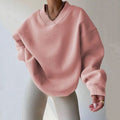 Person wearing an oversized soft pink v-neck sweatshirt with dropped shoulders and ribbed cuffs over cream ribbed leggings._0