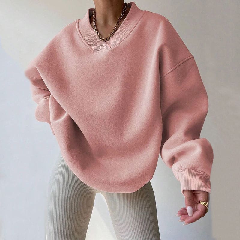 Person wearing an oversized soft pink v-neck sweatshirt with dropped shoulders and ribbed cuffs over cream ribbed leggings._0