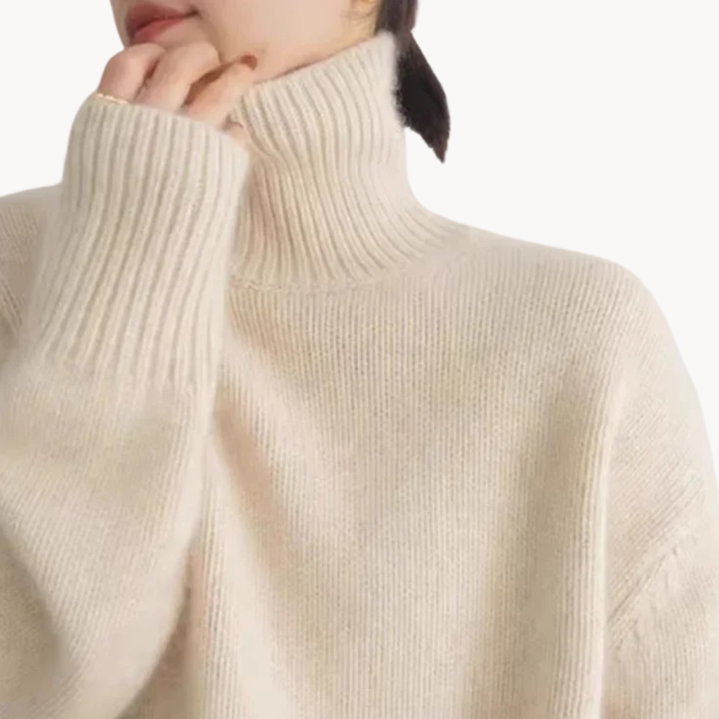 Woman wearing a cream oversized turtleneck sweater with ribbed detailing and relaxed fit, styled with a tan handbag._1