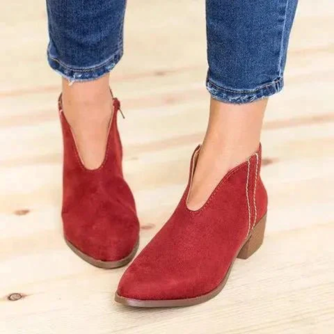 Red V-cut low heel ankle boots paired with cropped blue jeans, shown from a front three-quarter angle.