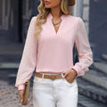 Pink V-neck blouse with textured sheer sleeves, styled with white jeans and a tan belt.
