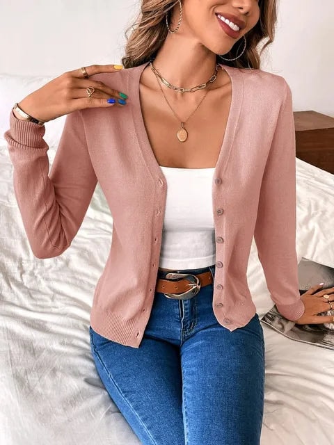 Blush pink button-front cardigan styled open over a white top.