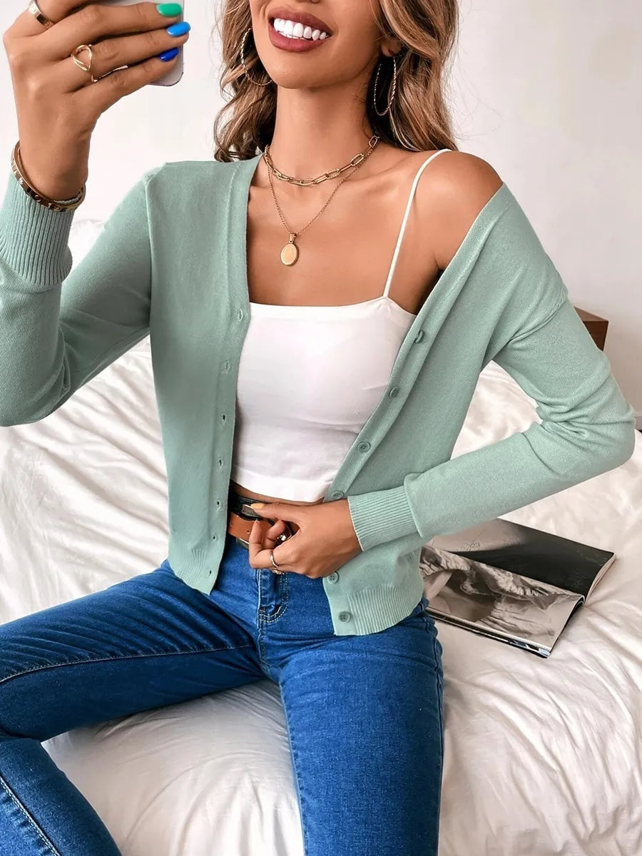Sage green cardigan worn open over a white camisole, showing its button front and long sleeves.