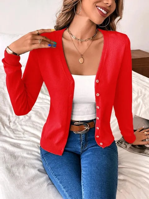 Red V-neck cardigan worn open over a white top with blue jeans.