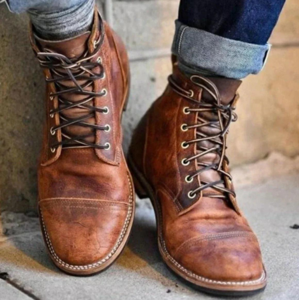 Pair of brown vintage-inspired lace-up ankle boots with cap-toe stitching and rolled jeans.