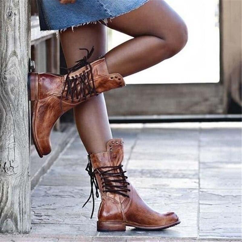 A pair of mid calf lace-up boots with a vintage distressed finish and stacked heel worn on a model._2