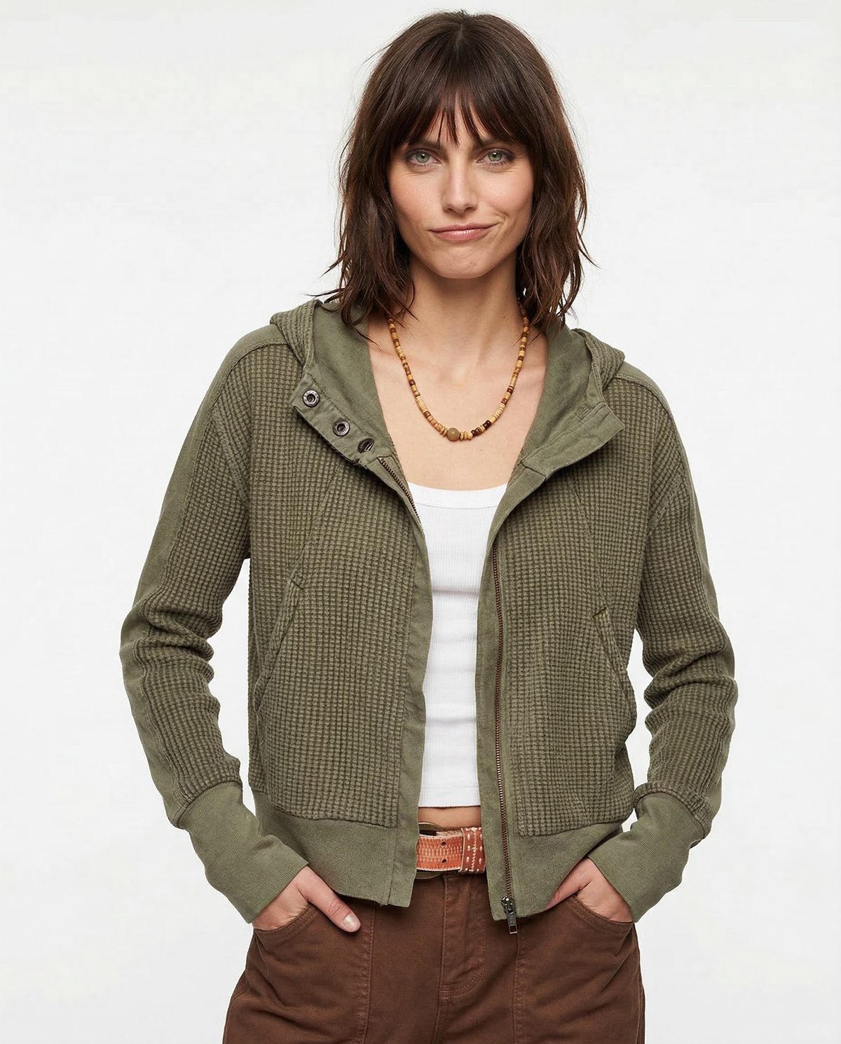 Model wearing an olive green waffle knit zip-up hoodie with cropped length and hood, styled with brown pants._12