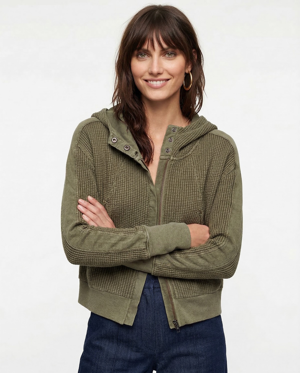 Model wearing an olive green waffle knit zip-up hoodie with cropped length and hood, styled with brown pants._13