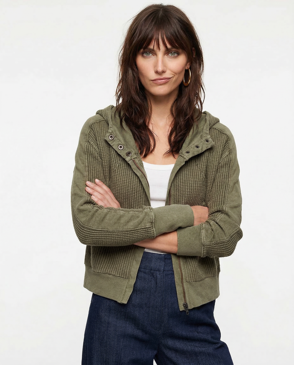 Model wearing an olive green waffle knit zip-up hoodie with cropped length and hood, styled with brown pants._14