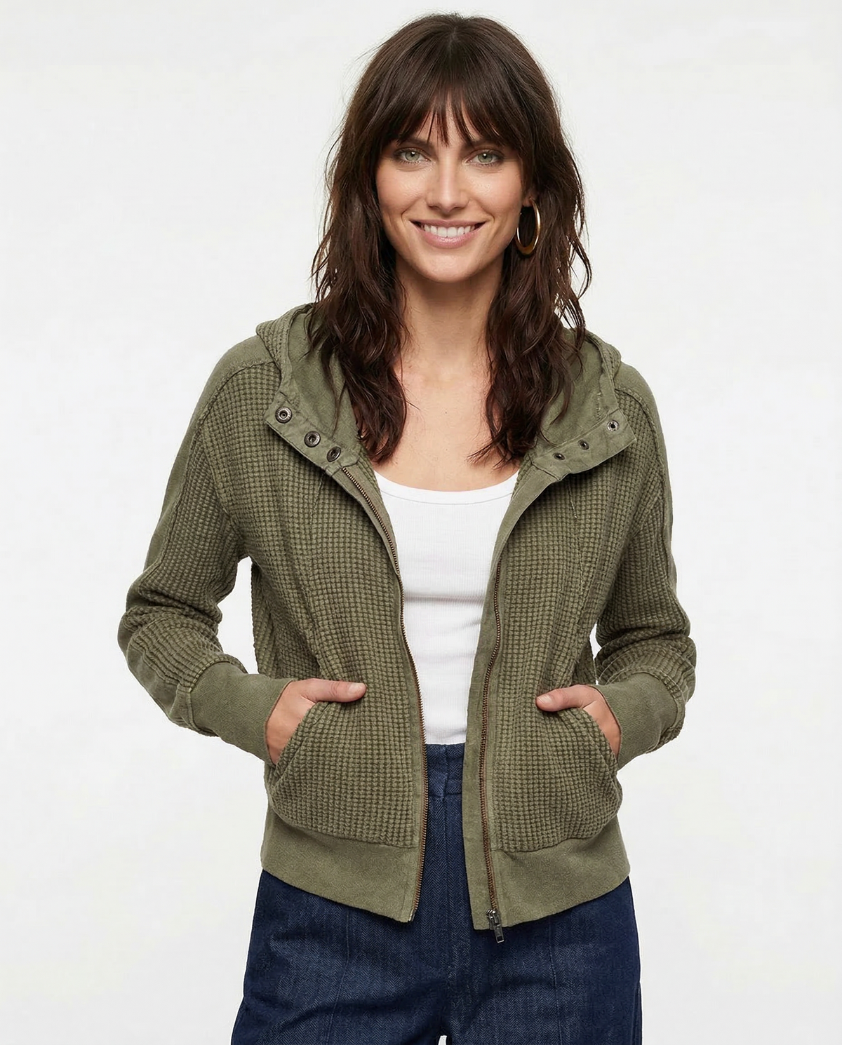 Model wearing an olive green waffle knit zip-up hoodie with cropped length and hood, styled with brown pants._15