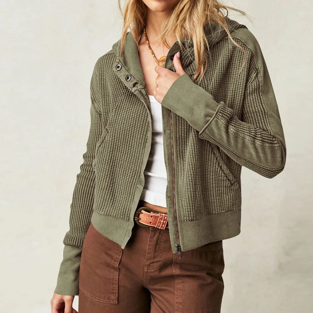 Model wearing an olive green waffle knit zip-up hoodie with cropped length and hood, styled with brown pants._16