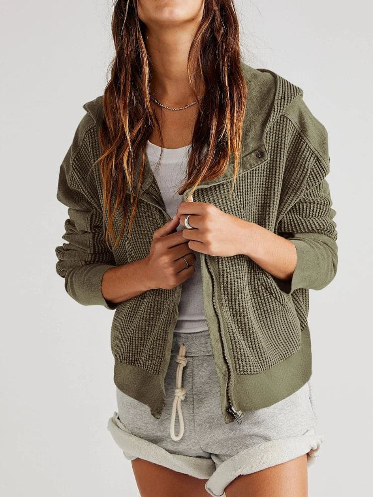 Model wearing an olive green waffle knit zip-up hoodie with cropped length and hood, styled with brown pants._17