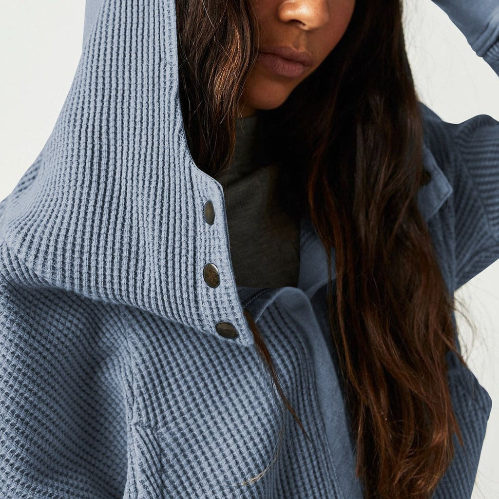 Model wearing an olive green waffle knit zip-up hoodie with cropped length and hood, styled with brown pants._26