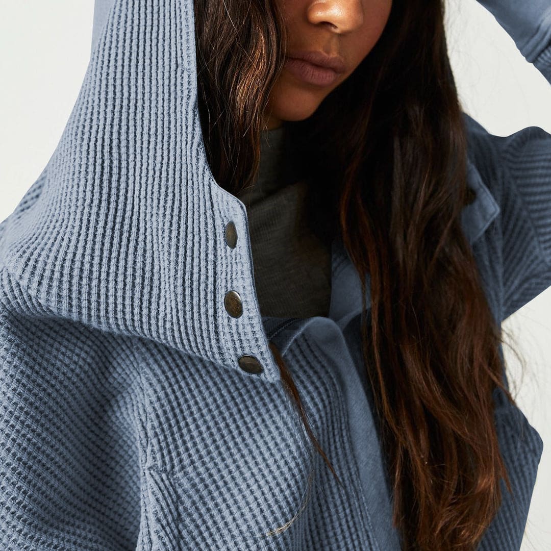 Model wearing an olive green waffle knit zip-up hoodie with cropped length and hood, styled with brown pants._26