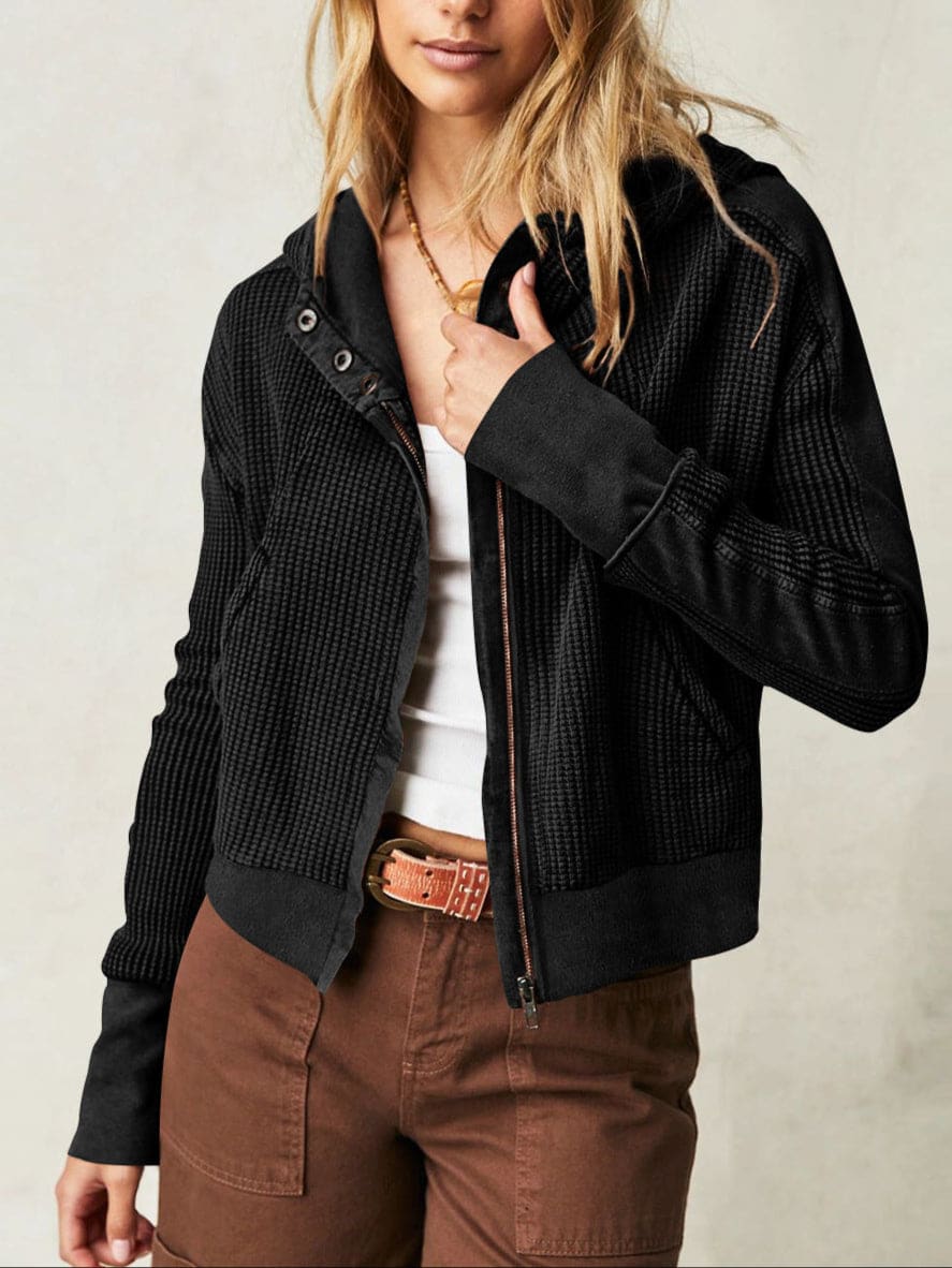 Model wearing an olive green waffle knit zip-up hoodie with cropped length and hood, styled with brown pants._30