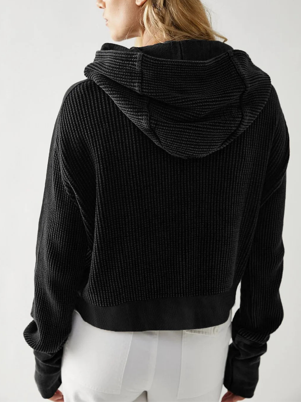 Model wearing an olive green waffle knit zip-up hoodie with cropped length and hood, styled with brown pants._33