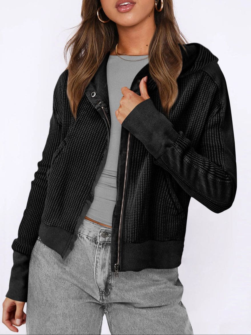 Model wearing an olive green waffle knit zip-up hoodie with cropped length and hood, styled with brown pants._35