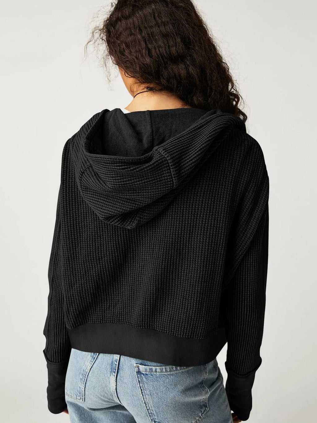 Model wearing an olive green waffle knit zip-up hoodie with cropped length and hood, styled with brown pants._36