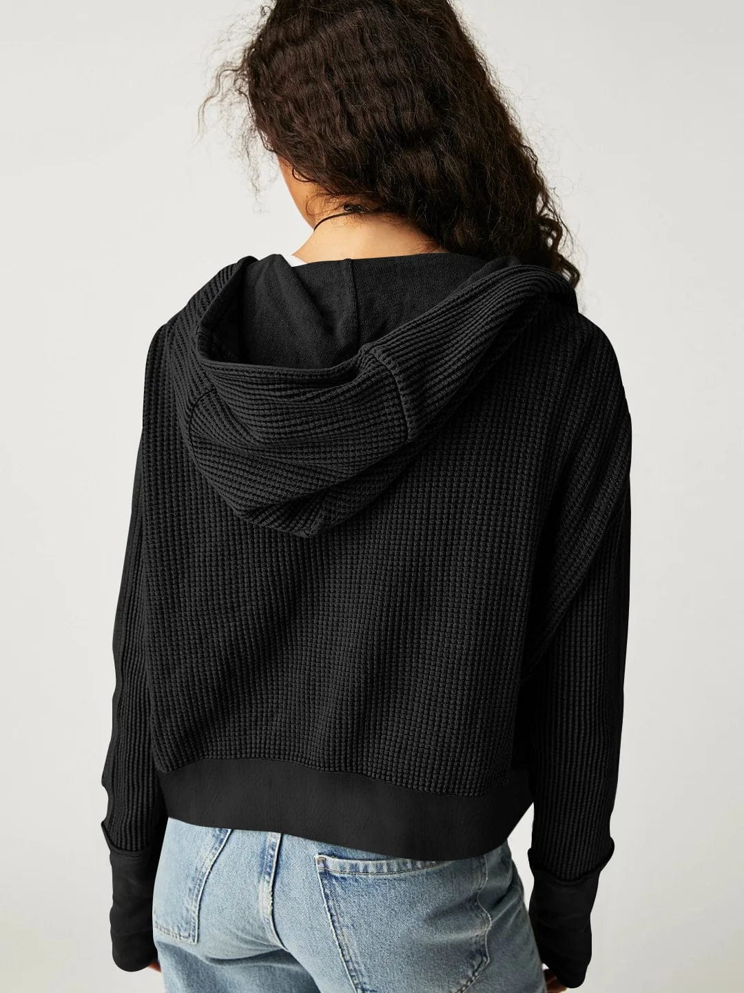 Model wearing an olive green waffle knit zip-up hoodie with cropped length and hood, styled with brown pants._36