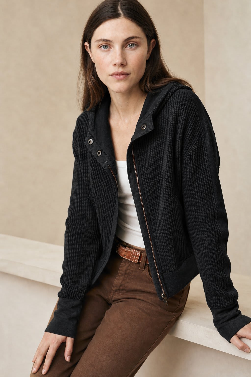 Model wearing an olive green waffle knit zip-up hoodie with cropped length and hood, styled with brown pants._4