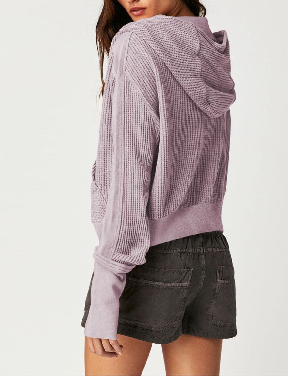 Model wearing an olive green waffle knit zip-up hoodie with cropped length and hood, styled with brown pants._40