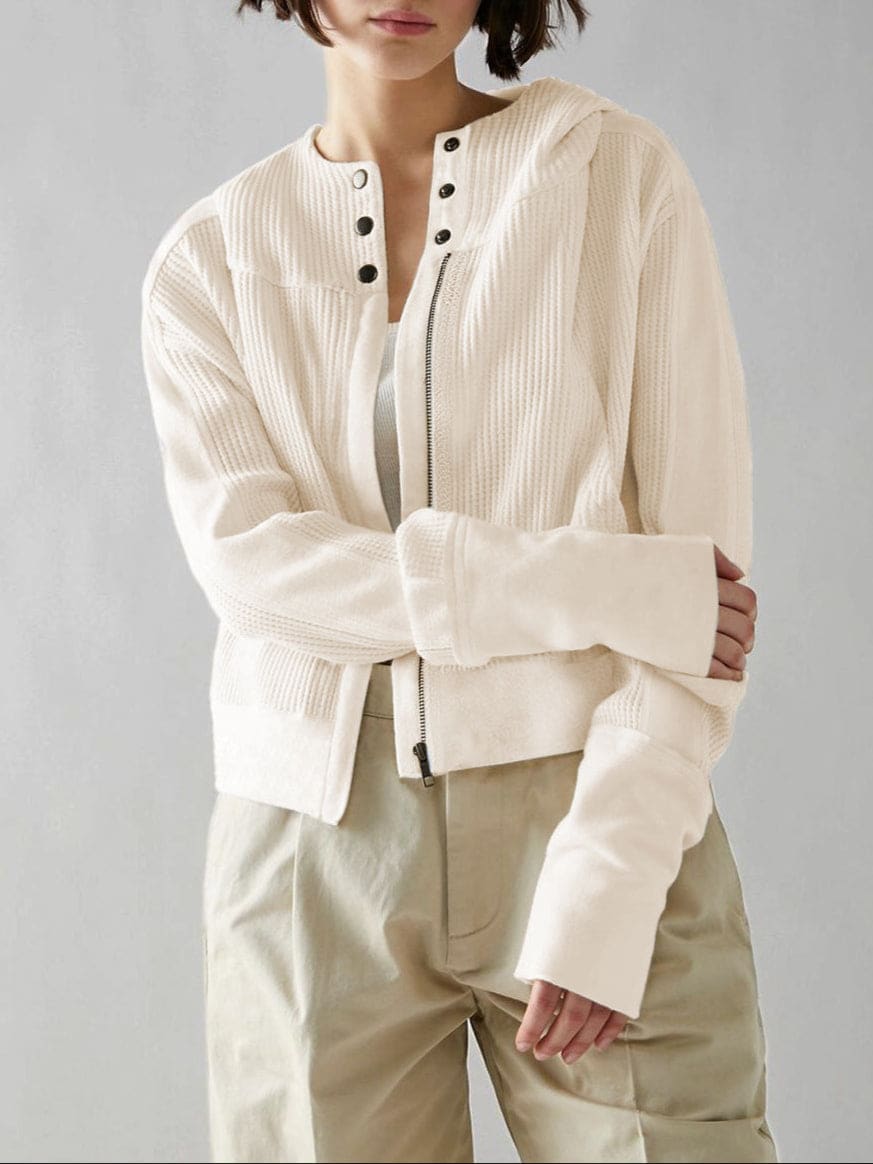 Model wearing an olive green waffle knit zip-up hoodie with cropped length and hood, styled with brown pants._44