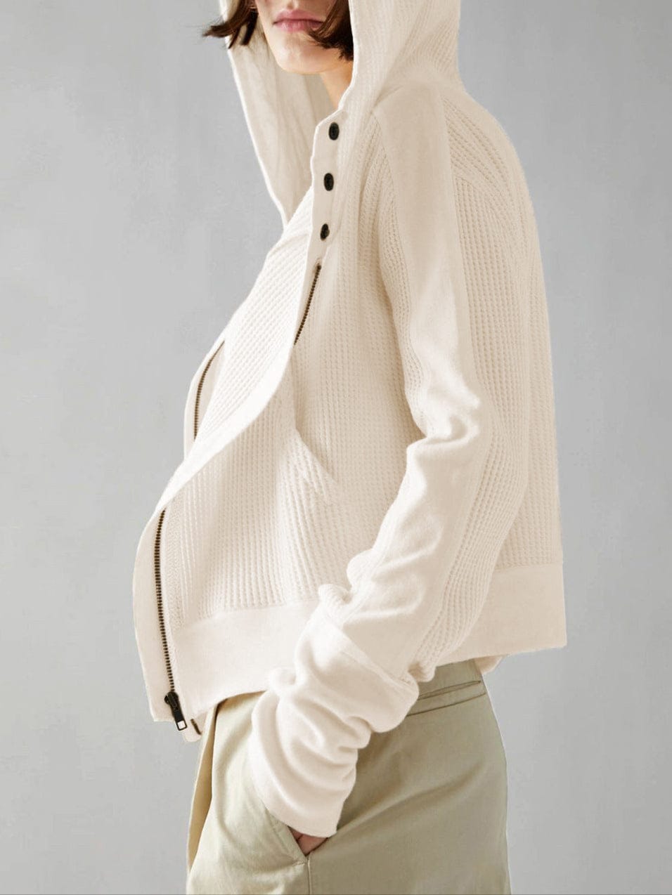 Model wearing an olive green waffle knit zip-up hoodie with cropped length and hood, styled with brown pants._45