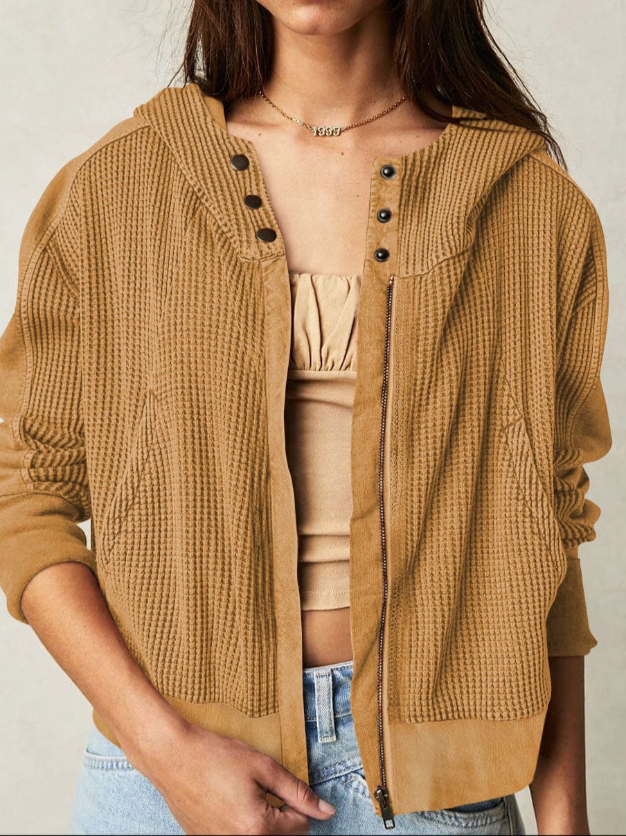 Model wearing an olive green waffle knit zip-up hoodie with cropped length and hood, styled with brown pants._50