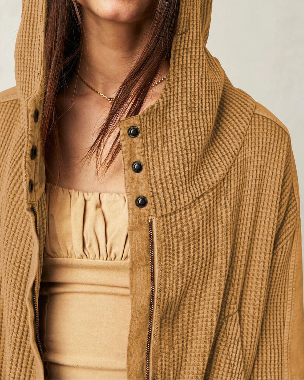 Model wearing an olive green waffle knit zip-up hoodie with cropped length and hood, styled with brown pants._52