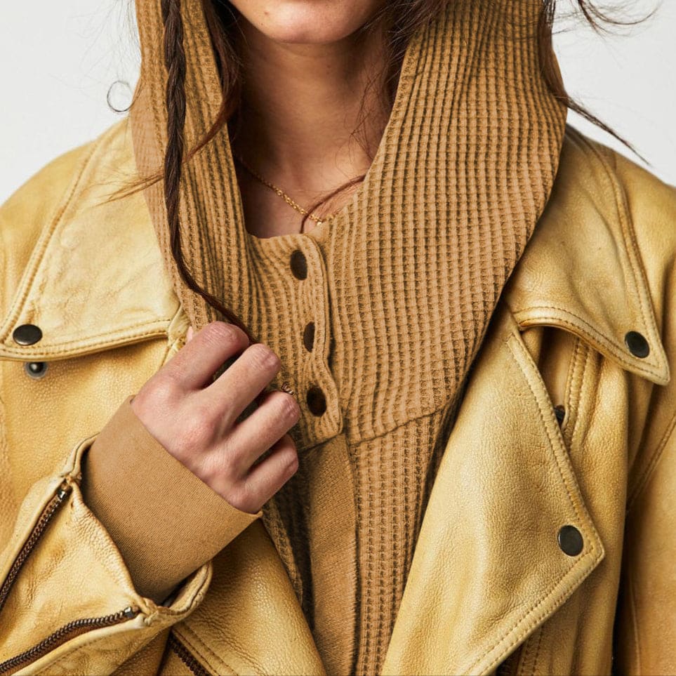 Model wearing an olive green waffle knit zip-up hoodie with cropped length and hood, styled with brown pants._53