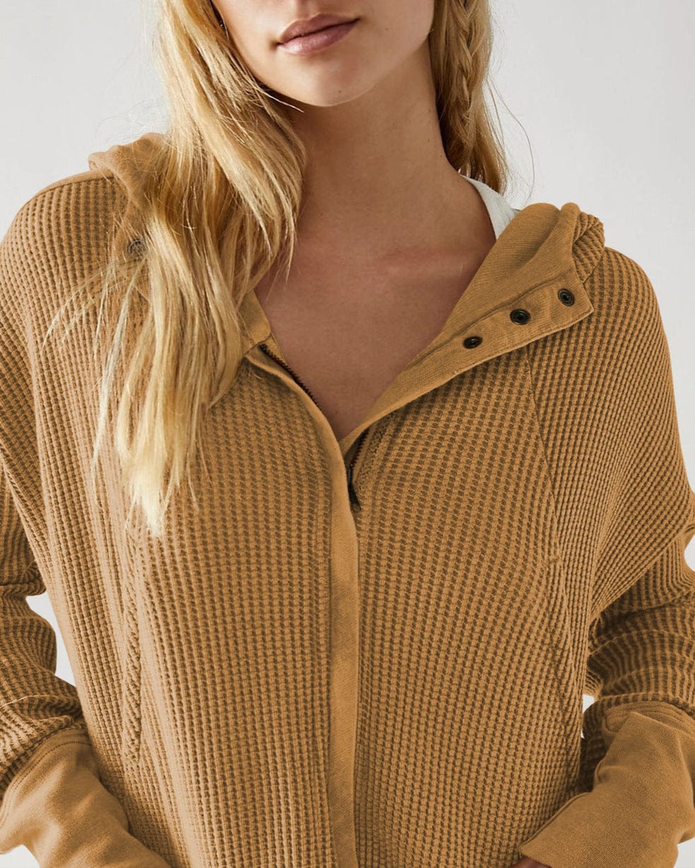 Model wearing an olive green waffle knit zip-up hoodie with cropped length and hood, styled with brown pants._54