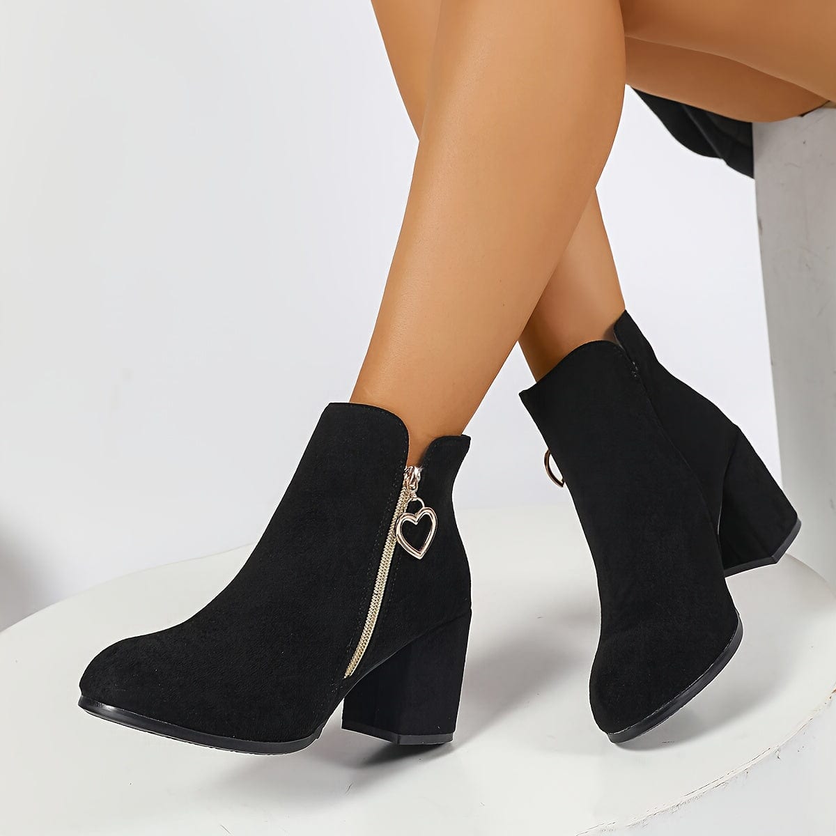 Pair of ankle boots with block heel, side zipper with gold heart charm, and elastic panel for easy wear._3