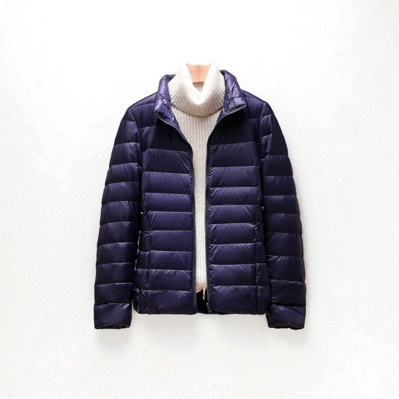 A quilted puffer jacket with a high collar and front zip closure shown layered over a sweater._0