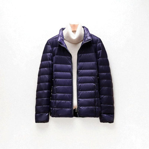 A quilted puffer jacket with a high collar and front zip closure shown layered over a sweater._0