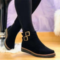 Woman wearing ankle boots with double buckle detail and flat sole, styled with dark leggings on a wooden floor._0