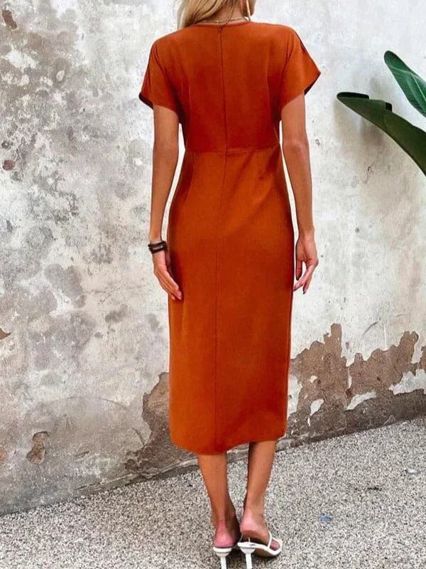 Woman wearing a rust orange wrap midi dress with v neckline and short sleeves, styled with statement earrings and a clutch_4